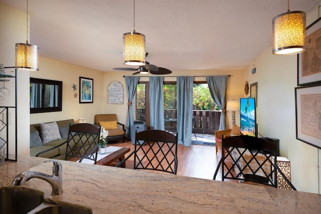 dining room with sink, a textured ceiling, hardwood / wood-style floors, and ceiling fan