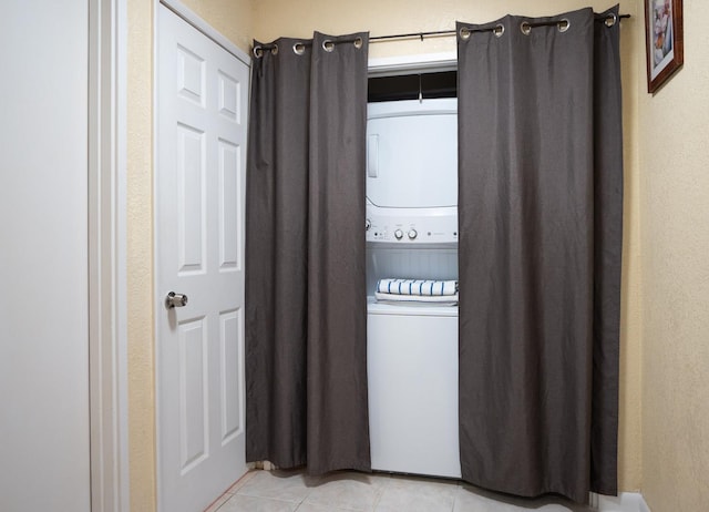 laundry room with light tile patterned flooring and stacked washer / dryer