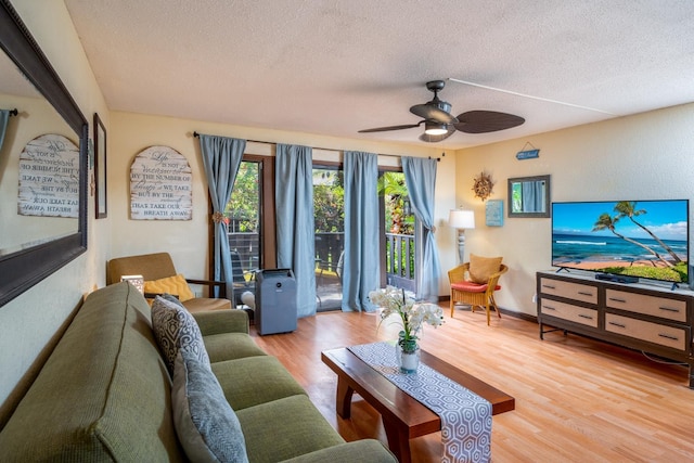 living room with ceiling fan, a textured ceiling, and light wood-type flooring