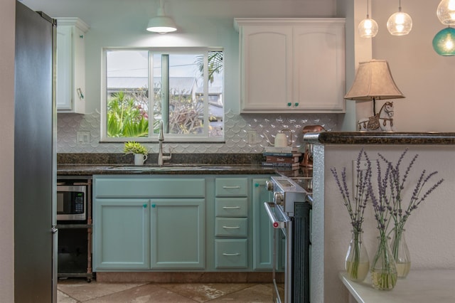 kitchen featuring pendant lighting, sink, white cabinetry, and tasteful backsplash