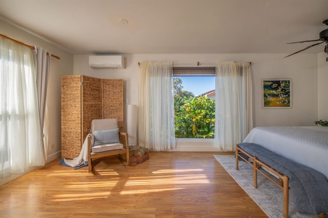 bedroom featuring light wood-type flooring, an AC wall unit, and ceiling fan