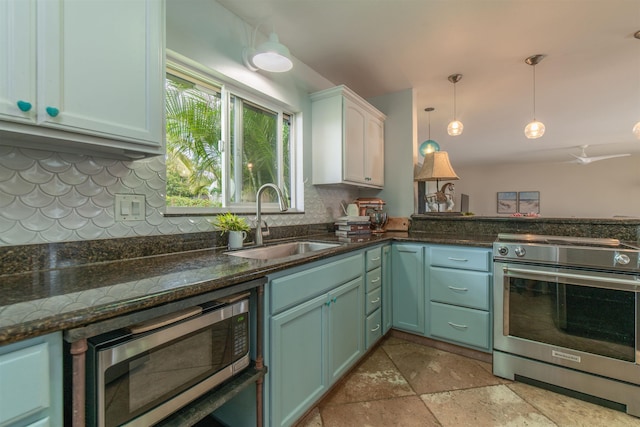 kitchen with hanging light fixtures, sink, white cabinets, dark stone counters, and stainless steel appliances