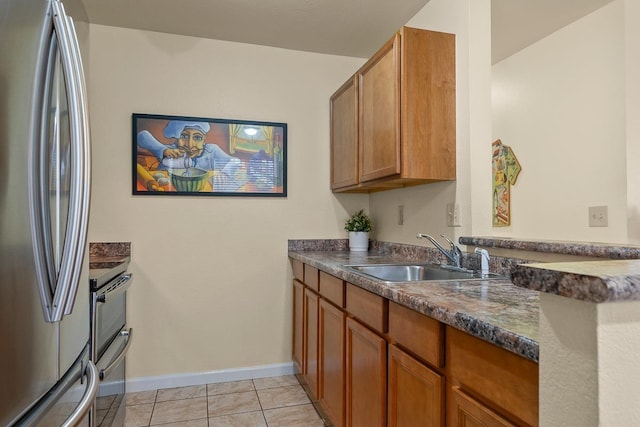 480 Kenolio Rd Unit 21-101, Kihei, HI 96753 - kitchen featuring stainless steel appliances, a sink, baseboards, dark countertops, and brown cabinets