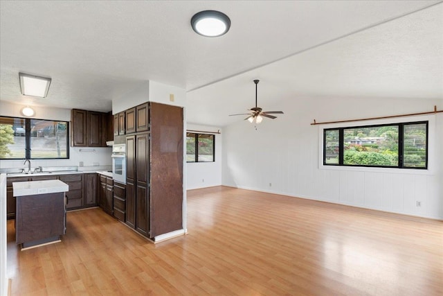 kitchen with lofted ceiling, a healthy amount of sunlight, light wood-type flooring, and ceiling fan