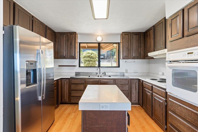 kitchen with light wood-type flooring, white appliances, a center island, and sink