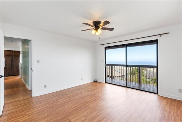 empty room featuring ceiling fan, a water view, and light hardwood / wood-style floors