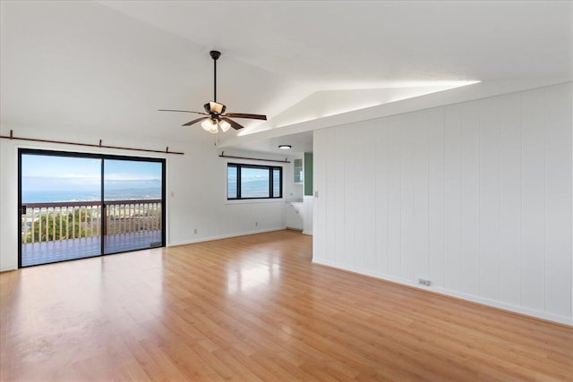 unfurnished room with ceiling fan, wood walls, lofted ceiling, and light wood-type flooring