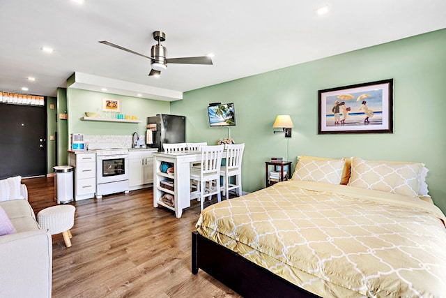 bedroom with hardwood / wood-style flooring, sink, and stainless steel fridge