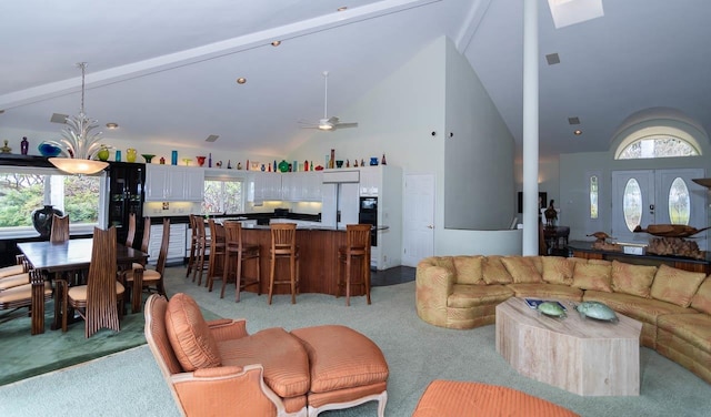 carpeted living room with high vaulted ceiling, ceiling fan, and a healthy amount of sunlight