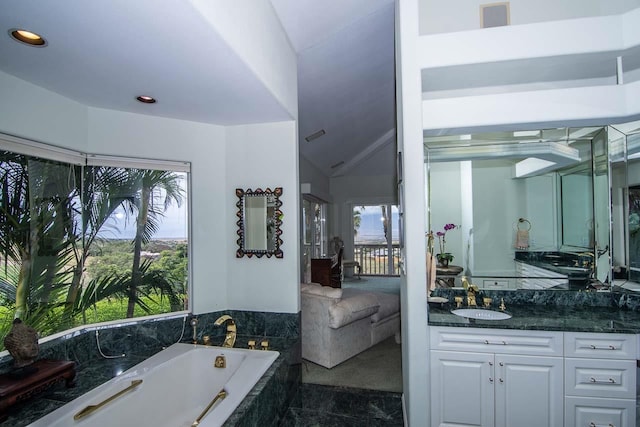 bathroom featuring tile flooring, vaulted ceiling, vanity, and tiled bath