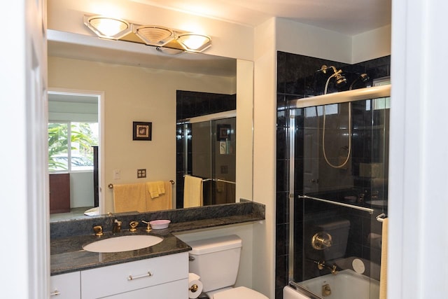 full bathroom with toilet, large vanity, and bath / shower combo with glass door