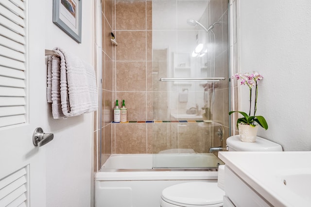 full bathroom with vanity, bath / shower combo with glass door, and toilet