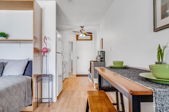 interior space with a textured ceiling, light wood-type flooring, ceiling fan, and white fridge