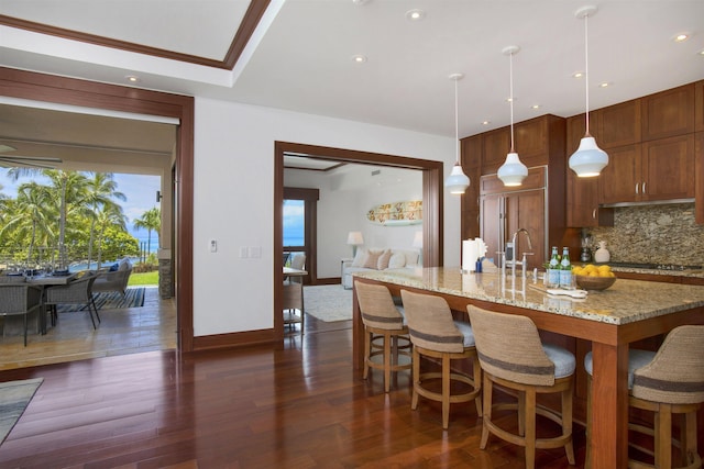 1 Bay Dr Unit 1205, Lahaina, HI 96761 - kitchen featuring backsplash, light stone counters, a center island with sink, hanging light fixtures, and a breakfast bar