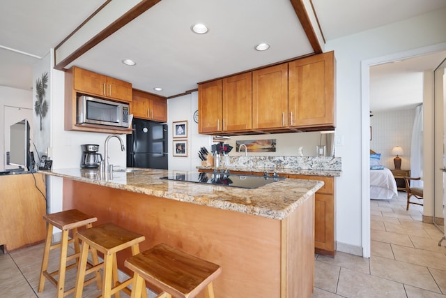 2450 S Kihei Rd Unit 506, Kihei, HI 96753 - kitchen featuring black appliances, light tile patterned floors, a sink, a kitchen bar, and light stone counters