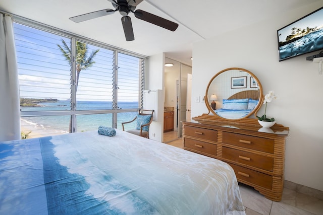 2450 S Kihei Rd Unit 506, Kihei, HI 96753 - bedroom featuring light tile patterned flooring, ceiling fan, ensuite bath, a wall of windows, and a water view