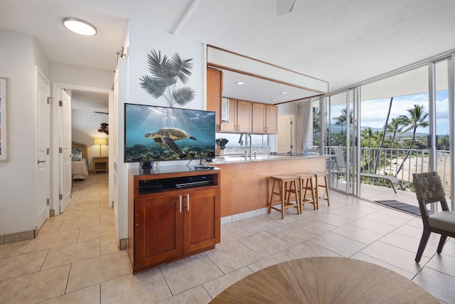 2450 S Kihei Rd Unit 506, Kihei, HI 96753 - kitchen featuring a wall of windows, a sink, a breakfast bar area, light tile patterned floors, and light stone countertops