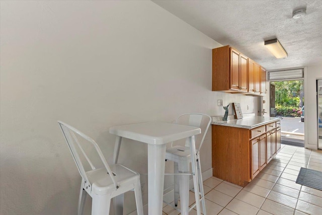 715 S Kihei Rd Unit D135, Kihei, HI 96753 - kitchen featuring a textured ceiling, light countertops, light tile patterned floors, and brown cabinets