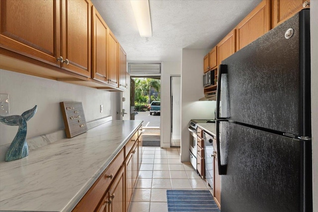 715 S Kihei Rd Unit D135, Kihei, HI 96753 - kitchen with freestanding refrigerator, light tile patterned floors, brown cabinetry, stainless steel range with electric cooktop, and a textured ceiling