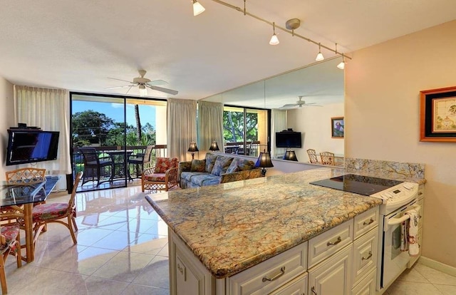 kitchen with ceiling fan, light tile floors, light stone countertops, and expansive windows