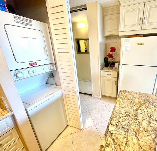 laundry area featuring stacked washer and dryer and light tile flooring