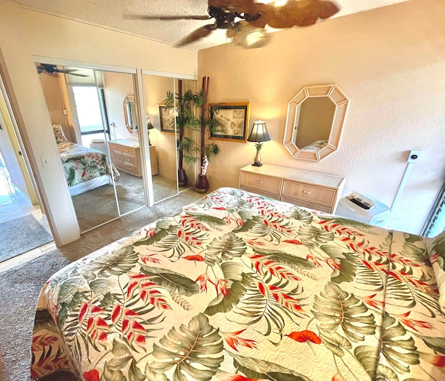 carpeted bedroom with ceiling fan, two closets, and a textured ceiling