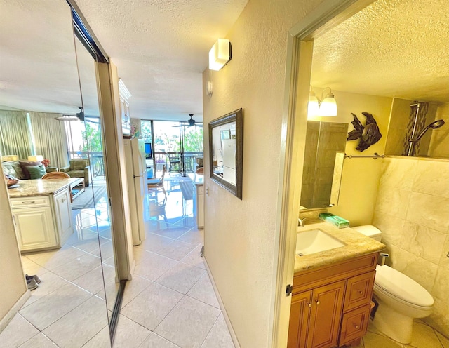 interior space with ceiling fan, toilet, large vanity, and tile floors