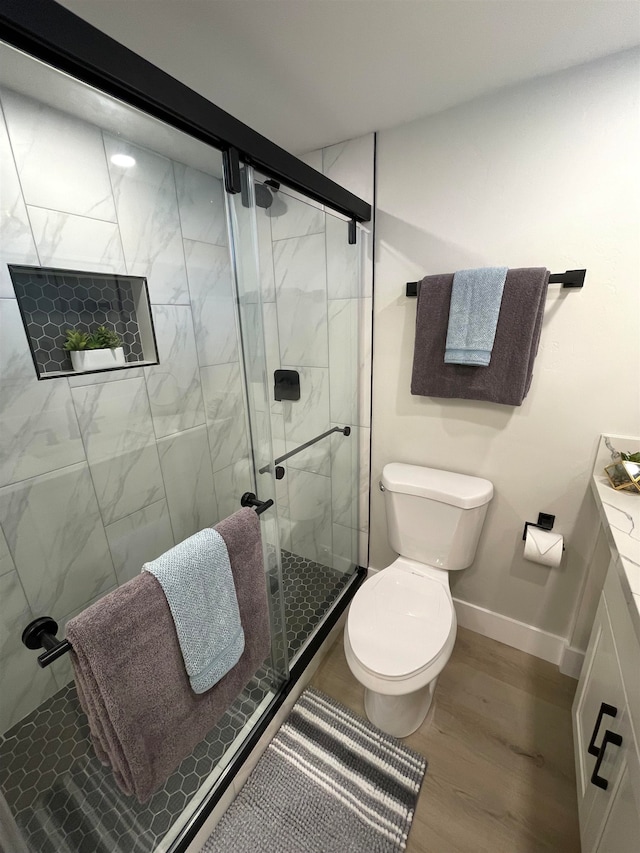 bathroom featuring vanity, hardwood / wood-style flooring, toilet, and a shower with door