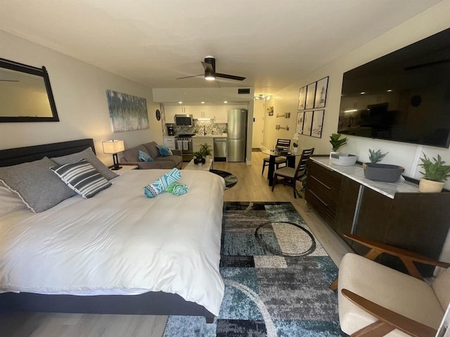 bedroom with visible vents, light wood-style floors, and freestanding refrigerator