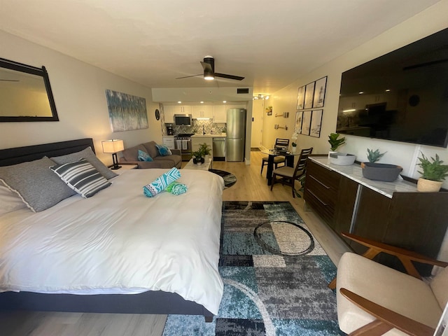 bedroom with ceiling fan, light hardwood / wood-style flooring, and stainless steel fridge