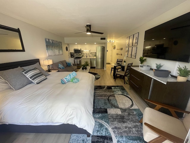 bedroom featuring light wood-style flooring, visible vents, and freestanding refrigerator