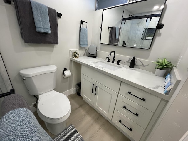 bathroom featuring toilet, a stall shower, vanity, and baseboards