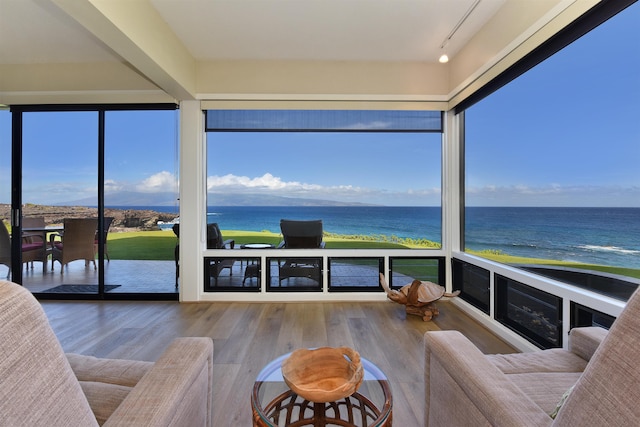 sunroom / solarium featuring a water view, a beach view, and rail lighting