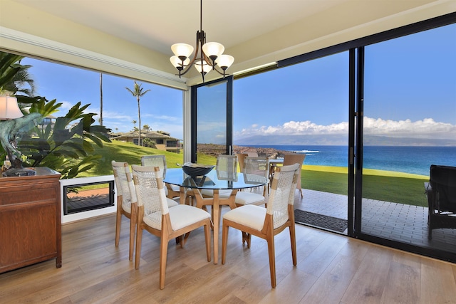 sunroom featuring a water view, a view of the beach, and a notable chandelier