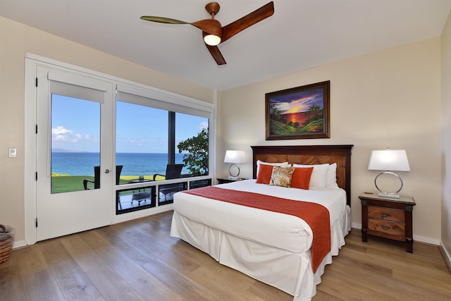 bedroom featuring ceiling fan, wood-type flooring, a water view, and access to outside