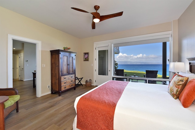 bedroom featuring a water view, hardwood / wood-style floors, and ceiling fan