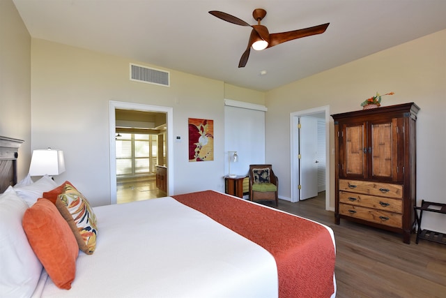 bedroom featuring ceiling fan, ensuite bath, a closet, and dark hardwood / wood-style flooring