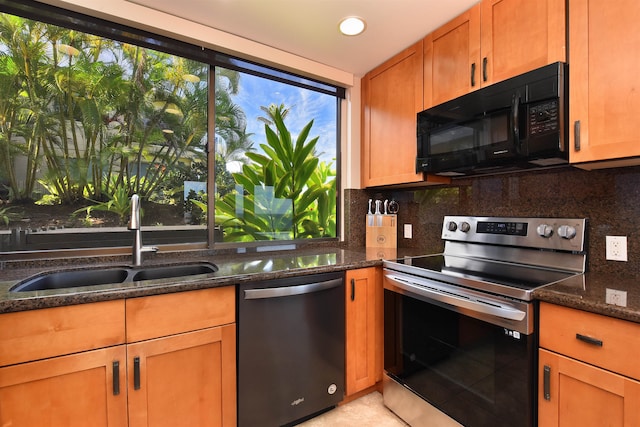 kitchen with stainless steel appliances, dark stone countertops, a healthy amount of sunlight, and sink