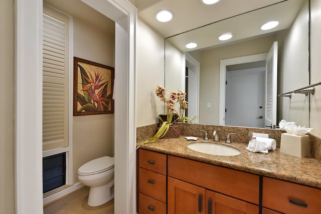 bathroom with toilet, vanity, and hardwood / wood-style flooring