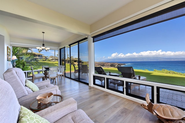 sunroom / solarium featuring a water view and a notable chandelier