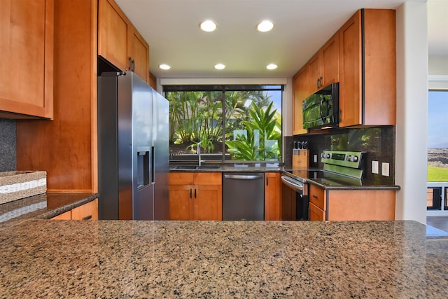 kitchen featuring dark stone counters, a healthy amount of sunlight, appliances with stainless steel finishes, and tasteful backsplash