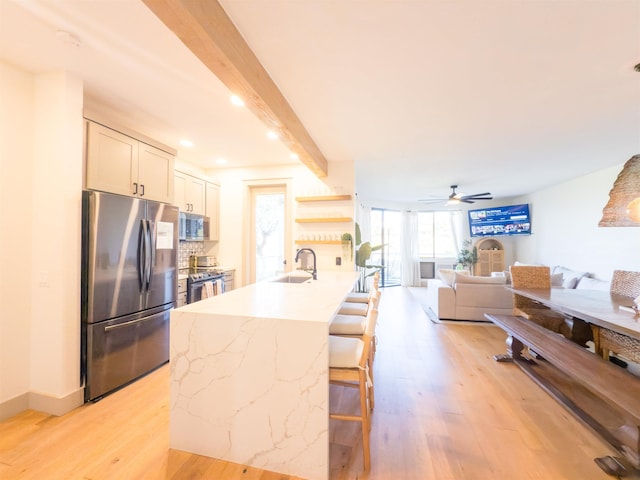 kitchen with beamed ceiling, a kitchen bar, white cabinets, sink, and stainless steel appliances