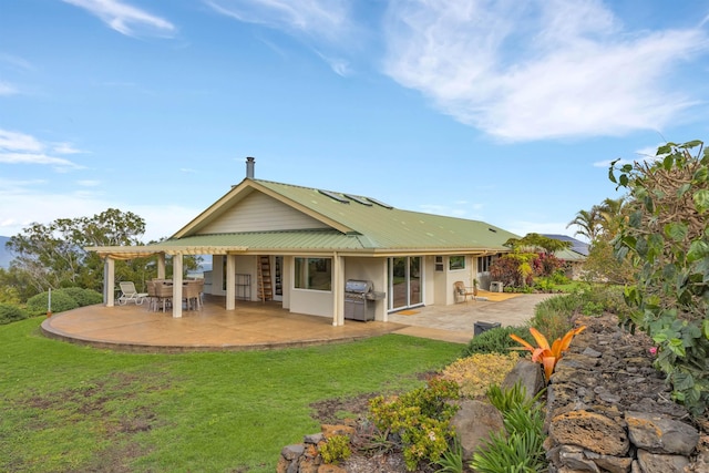 back of property with metal roof, a patio, a lawn, and area for grilling