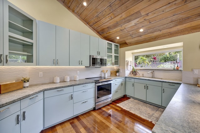 kitchen featuring light countertops, appliances with stainless steel finishes, a sink, and glass insert cabinets