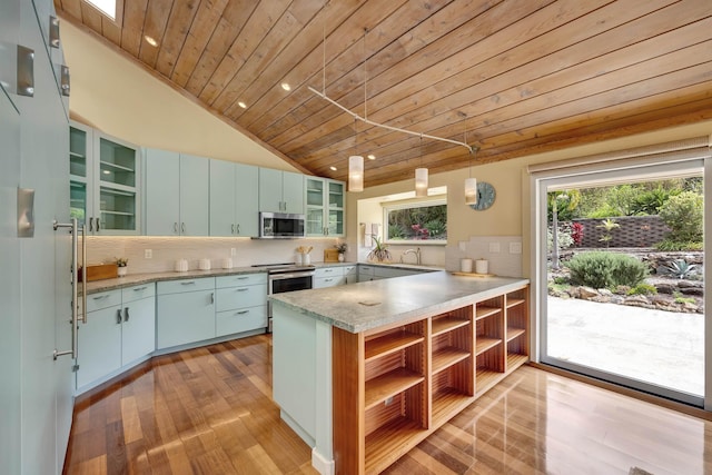 kitchen featuring glass insert cabinets, a peninsula, stainless steel appliances, decorative backsplash, and decorative light fixtures