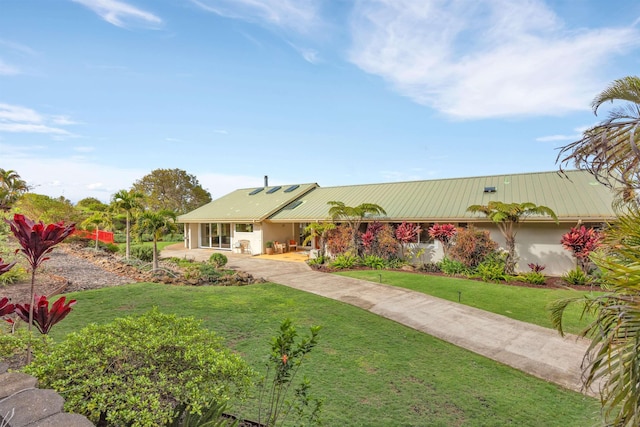 view of front of house with metal roof, a front lawn, and stucco siding