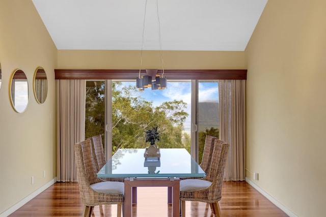 dining room with a notable chandelier, baseboards, and wood finished floors