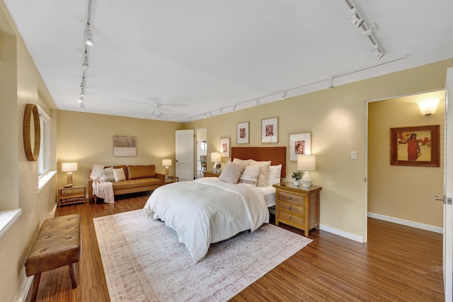 bedroom featuring dark wood-type flooring, rail lighting, and baseboards