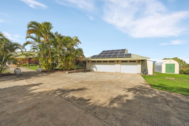 view of front of house with an outbuilding, metal roof, a storage shed, roof mounted solar panels, and a front lawn