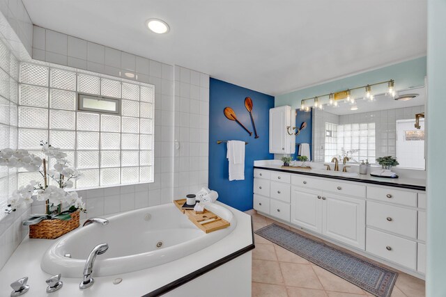 bathroom with a whirlpool tub, plenty of natural light, tile patterned flooring, and vanity